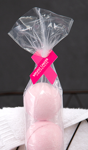 A pink ribbon-shaped bag closure securing a package of pink bath bombs.